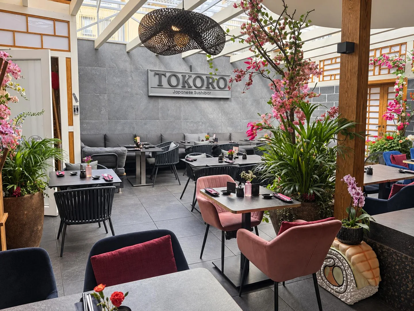Bright Tokoro dining room with plants, natural light and set tables